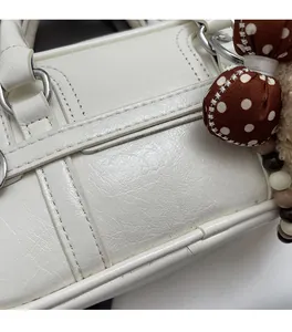 Détail du sac polochon en similicuir blanc avec texture litchi et nœud à pois chic