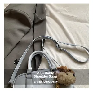 Detail of adjustable shoulder strap and cute bear charm on a light blue fashion bag