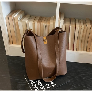 Close-up of brown litchi grain leather bucket bag with golden metal twist lock detail