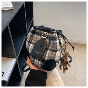 Détail du sac seau en tweed avec cordon en cuir, dorures et breloque lapin mignonne