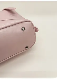 Detail shot of pink textured leather bag bottom with protective silver metal rivets