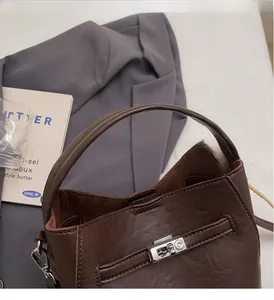 Detail of a brown leather bucket bag showing silver twist lock and soft suede interior