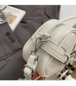 Gros plan d'un sac oreiller en cuir blanc plissé avec ferrures argentées et perles