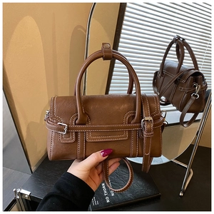 Detail view of brown vintage handbag with white contrast stitching and buckle strap