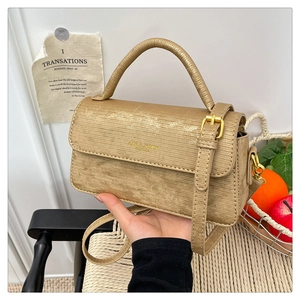 Detail of champagne gold textured leather handbag with gold logo and round handle