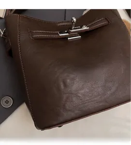 Close-up of dark brown leather bucket bag showing silver metal twist lock and texture