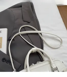 Détail du sac polochon blanc vintage montrant la texture du cuir et les boucles argentées
