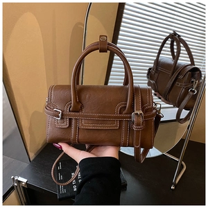 Detail of brown vintage leather handbag showing contrast white stitching and handle