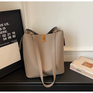 Close-up of litchi texture leather bucket bag with gold twist lock and shoulder straps