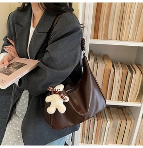 Detailed view of deep brown leather hobo bag with a cute plush bear charm on a model