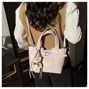 Detail view of pink leather bucket bag with a cute white teddy bear plush charm