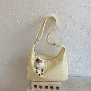 Détail du sac bandoulière plissé jaune clair en similicuir avec pendentif en peluche
