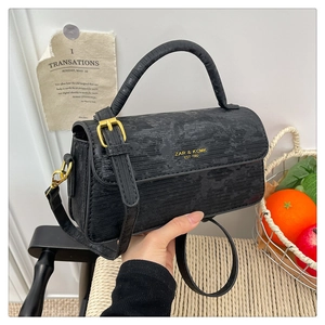 Detail of black embossed leather handbag with gold hardware and logo on flap cover