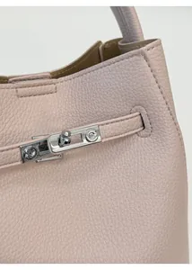 Detailed macro view of light pink lychee grain leather bag with silver metal swivel lock