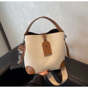 Top view of two-tone bucket bag featuring lychee texture leather and wide fabric strap