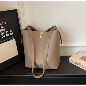 Close-up of beige bucket bag in lychee pattern leather with a gold twist lock closure