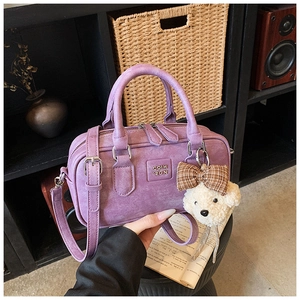 Close-up of purple Boston bag with COIH 2DN embossing and a cute teddy bear charm