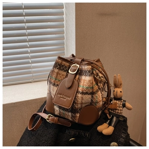 Détail du sac seau rétro à carreaux avec garniture en cuir et pendentif lapin mignon