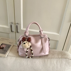 Detail of pink faux leather Boston bag with decorative bear charm and metal strap hooks