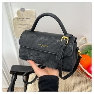 Detail of black vintage crossbody bag showing textured finish and golden logo hardware