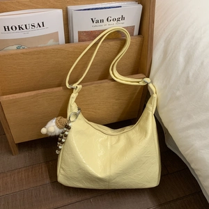 Détail du sac hobo jaune clair avec texture plissée douce et accessoire de charme en peluche