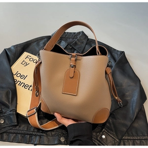 Close-up of pebble grain leather bucket bag with contrast trim and striped fabric strap