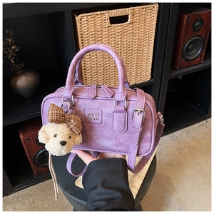Detail view of purple Boston style bag featuring textured material and cute plush puppy charm