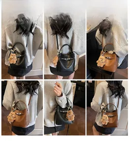 Detail view of bucket bag with lychee texture and cute plush bear keychain ornament