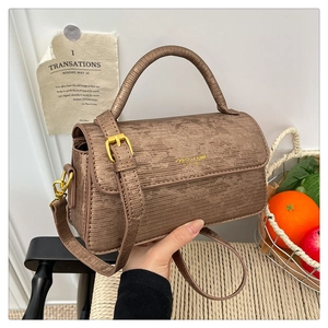 Detail of a brown textured faux leather handbag with golden hardware and brand logo