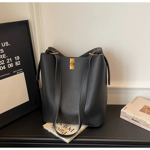 Close-up of black lychee grain leather bucket bag with elegant golden twist lock detail