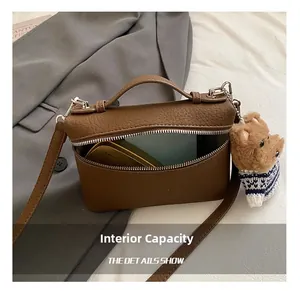 Detailansicht der Innenkapazität der braunen Umhängetasche mit kleinem Teddybär-Anhänger