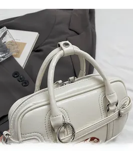 Détail d'un sac bowling en cuir crème texturé avec poignées métalliques et double fermeture