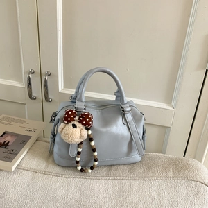 Close-up of light blue leather Boston bag with a cute plush dog charm and metal zipper