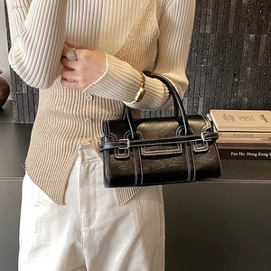 Detail of black leather handbag featuring contrast white stitching and metal buckles