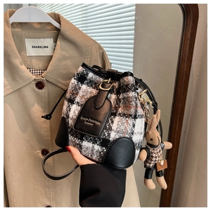 Détail du sac seau en tweed à carreaux avec cordon de serrage et étiquette en cuir