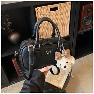 Detail shot of black leather commuter satchel with bear charm and silver hardware accents