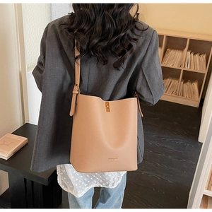 Detailed view of beige bucket bag with litchi texture and golden clasp closure