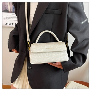 Detailed macro view of the cream-white crossbody bag with unique marble texture and gold logo