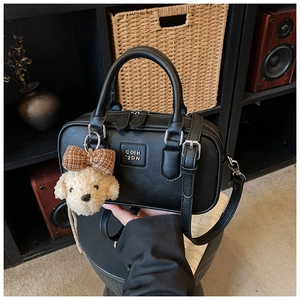 Detail of black PU crossbody bag with silver hardware and cute puppy plush charm