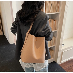 Detail of beige pebbled leather bucket bag with gold buckle and adjustable strap