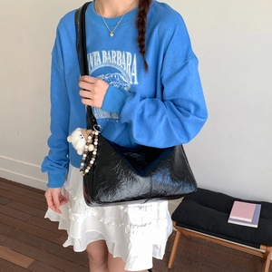 Sac à bandoulière noir brillant avec texture froissée et pendentif mouton