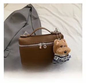 Detailansicht der braunen Ledertasche mit Litschi-Muster und Plüschhund-Anhänger