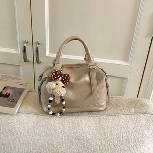 Detail of light khaki PU tote bag featuring a cute teddy bear charm and soft leather texture