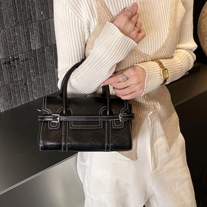 Close-up of black leather handbag with white contrast stitching and silver metal buckle