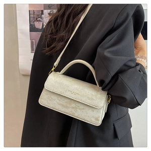 Detail view of cream-colored crossbody bag with wood grain texture and gold hardware