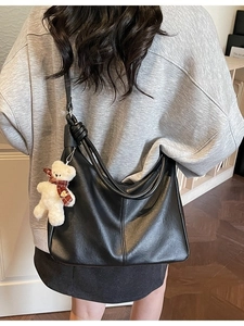 Minimalist black PU leather hobo bag with a cute bear charm shown on a female model