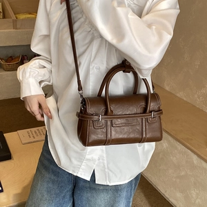 Detail of dark brown faux leather handbag showing white contrast stitching and buckle