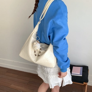 Détail du sac hobo blanc cassé avec texture plissée et accessoire pelucheux
