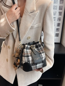 Sac seau en tweed noir et blanc avec pendentif lapin porté par un mannequin en extérieur