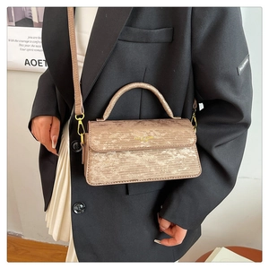 Detail of metallic champagne gold handbag with pleated texture and gold hardware details